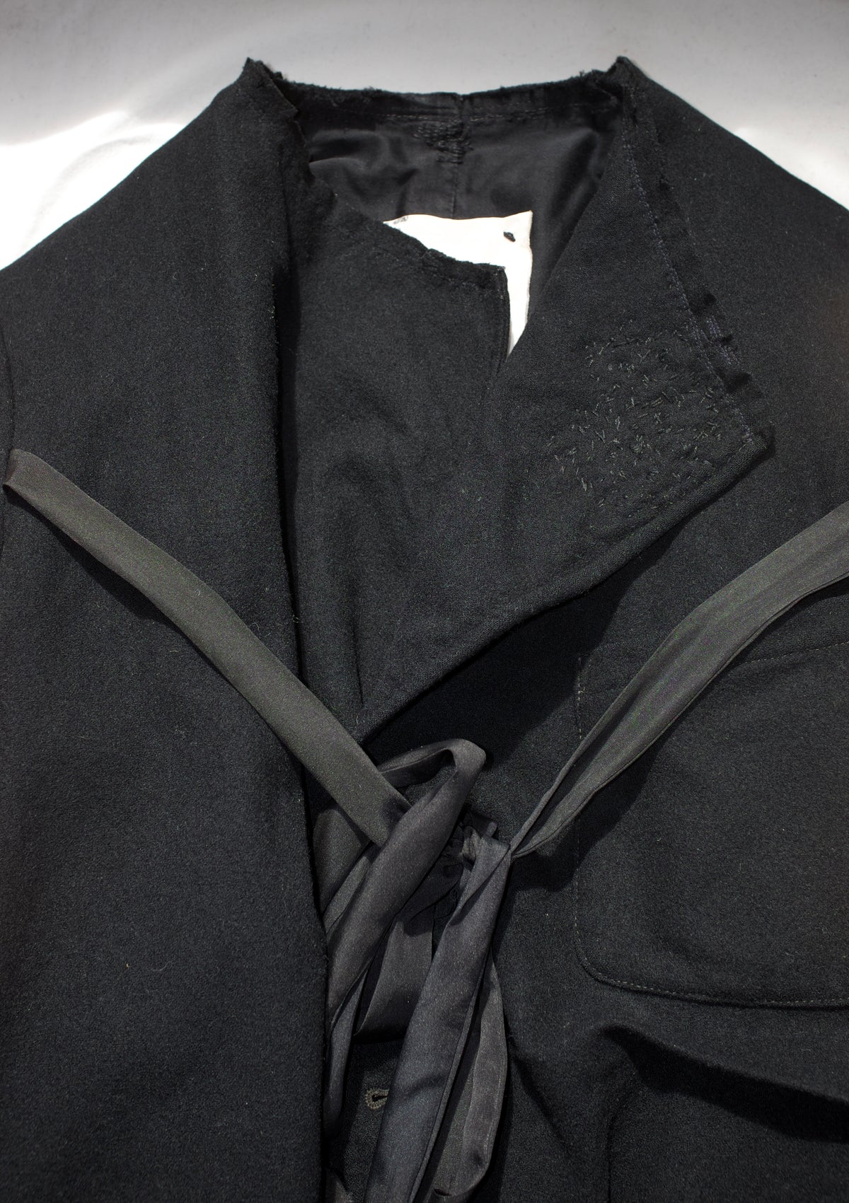 Black wool deconstructed jacket with silk chest tie and hand-stitched lapel